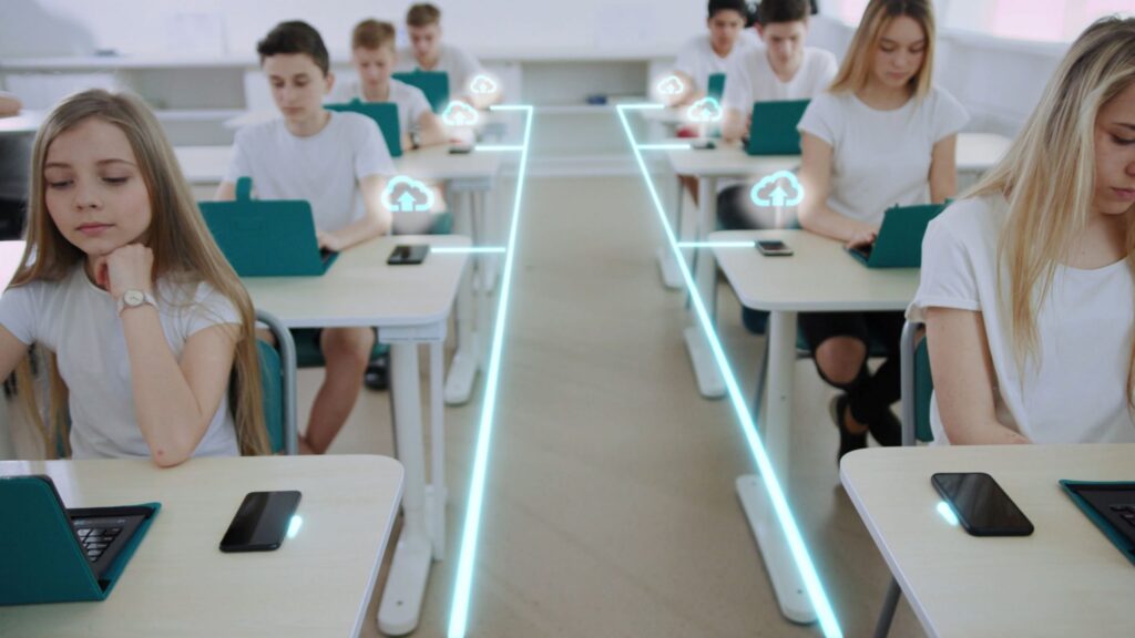 Estudiantes sentados en sus pupitres utilizando ordenadores portátiles en un aula. Líneas de neón digitales e iconos de nubes ilustran la conectividad y la tecnología, destacando un entorno moderno en el que conceptos como la verificación de edad en redes sociales son cada vez más relevantes.